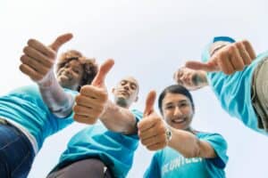Freudige Freiwillige geben Daumen hoch für soziales Engagement