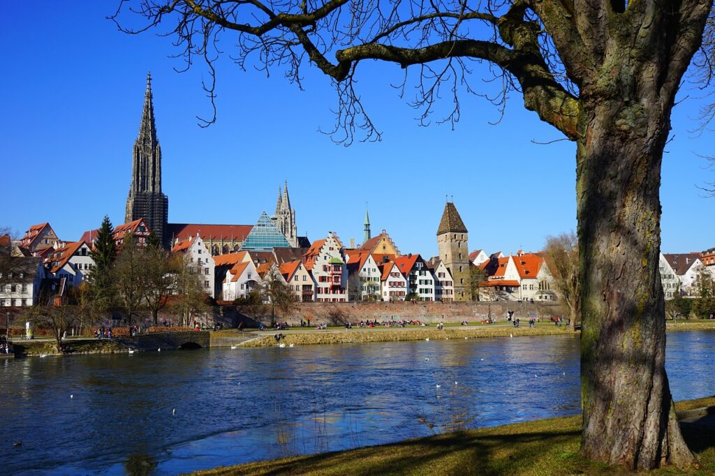Panoramaansicht der Ulmer Altstadt mit dem Münster im Hintergrund, ideal für die Präsentation von IT-Service & Systemhaus bei Ulm, umgeben von einer malerischen Flusslandschaft und historischen Gebäuden.