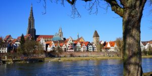 Panoramaansicht der Ulmer Altstadt mit dem Münster im Hintergrund, ideal für die Präsentation von IT-Service & Systemhaus bei Ulm, umgeben von einer malerischen Flusslandschaft und historischen Gebäuden.